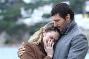 man standing in front of his wife protecting her during a tense group confrontation scenario