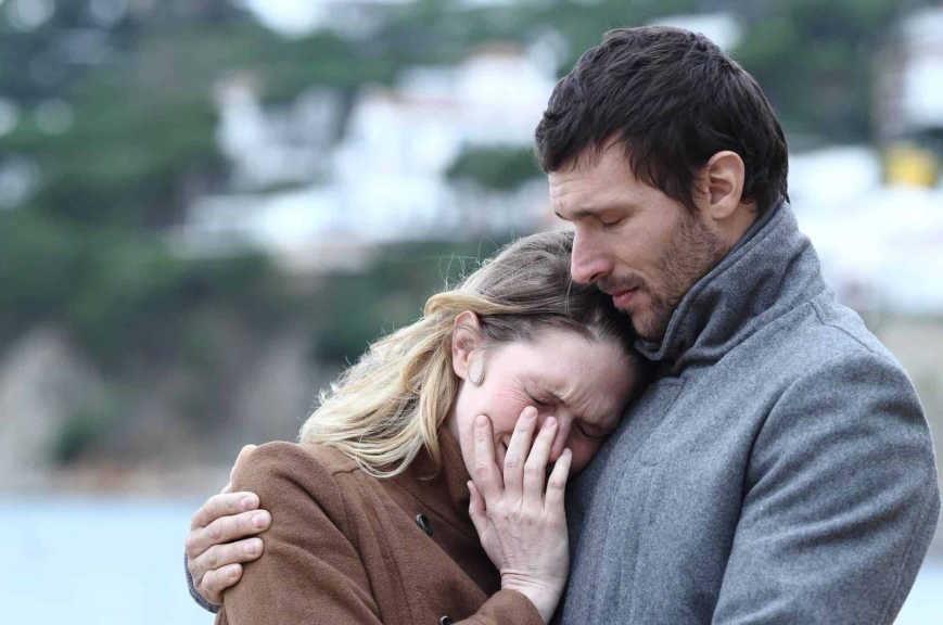 man standing in front of his wife protecting her during a tense group confrontation scenario